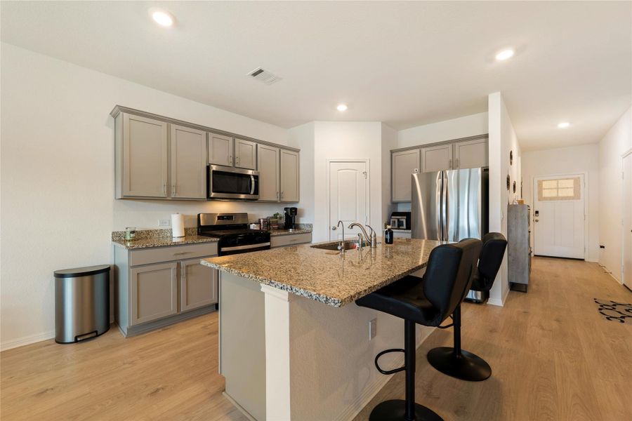 Kitchen features granite counters, stainless steel appliances, and an inviting island perfect for casual dining.