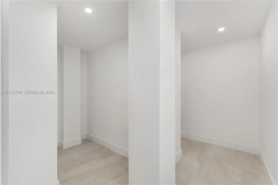 Interior space featuring neutral wall tones, recessed lighting, and wood-finish flooring Interior space featuring neutral wall tones, recessed lighting, and wood-finish flooring