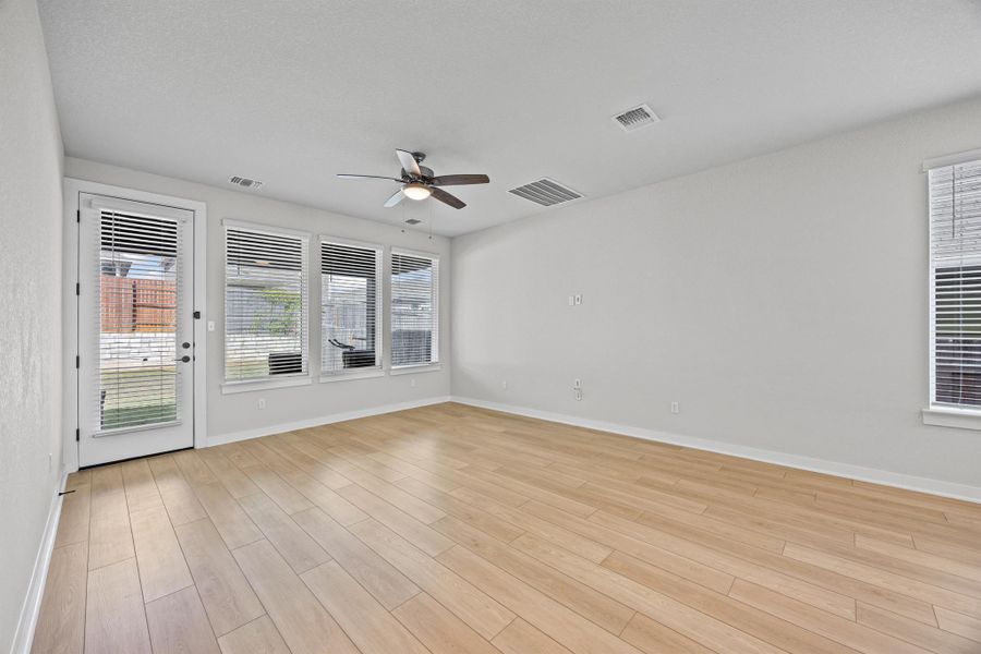 Living room with healthy amount of natural light, light wood-style flooring, and a ceiling fan