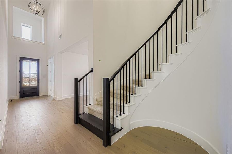 Foyer featuring wood-type flooring, plenty of natural light, stairway, and a high ceiling