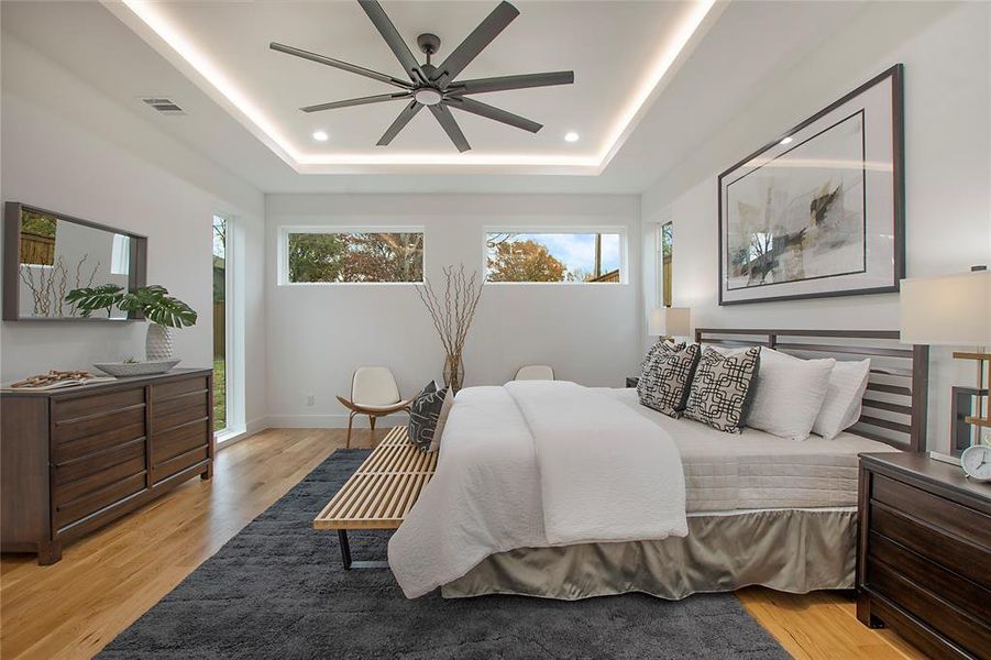 Bedroom featuring a raised ceiling, ceiling fan, and light hardwood / wood-style flooring