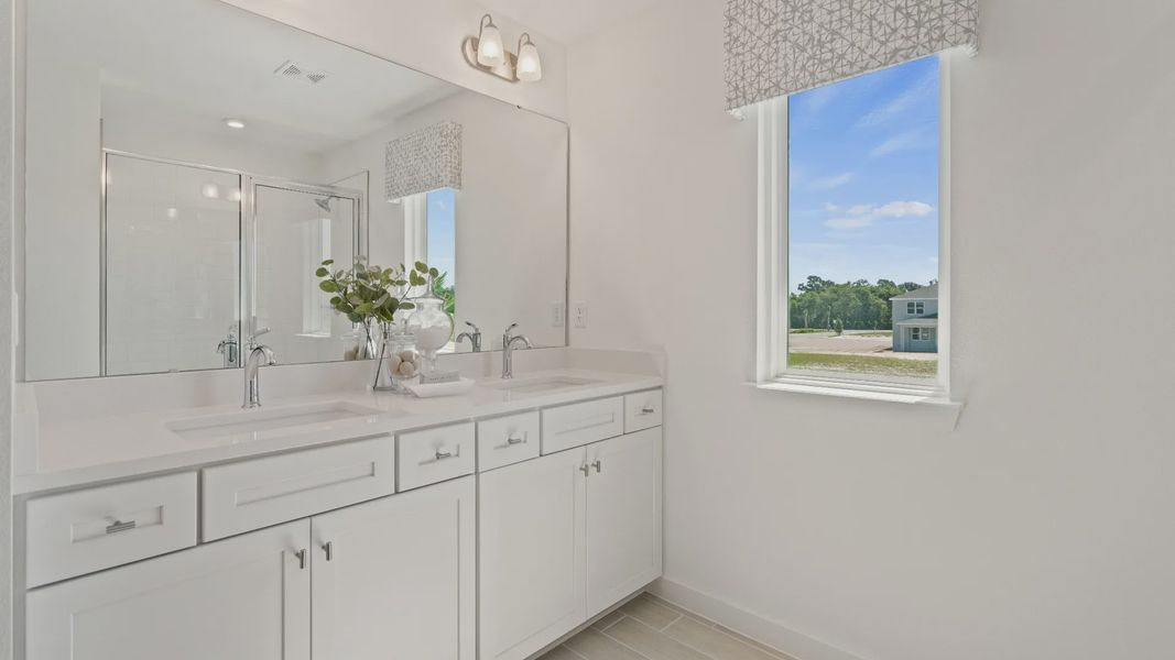 Primary bath with dual sink vanity, step-i shower and window n a DRB Homes Ambersweet model at the Trinity Place community. Primary bath with dual sink vanity, step-i shower and window n a DRB Homes Ambersweet model at the Trinity Place community.