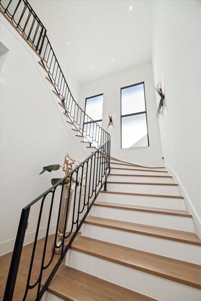 Modern floating staircase with wrought iron railing wood treads and translucent windows boscuring the views for privacy