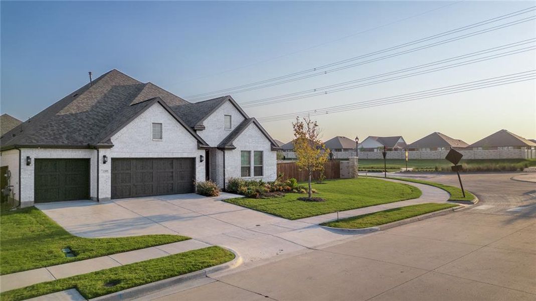 French country inspired facade featuring brick siding, concrete driveway, roof with shingles, and an attached garage French country inspired facade featuring brick siding, concrete driveway, roof with shingles, and an attached garage