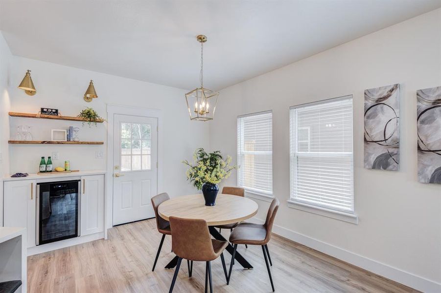 Dining room with light hardwood / wood-style floors, a chandelier, and wine cooler