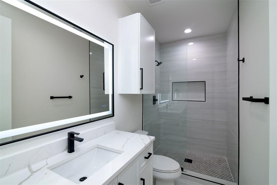 Bathroom with vanity, toilet, and a tile shower