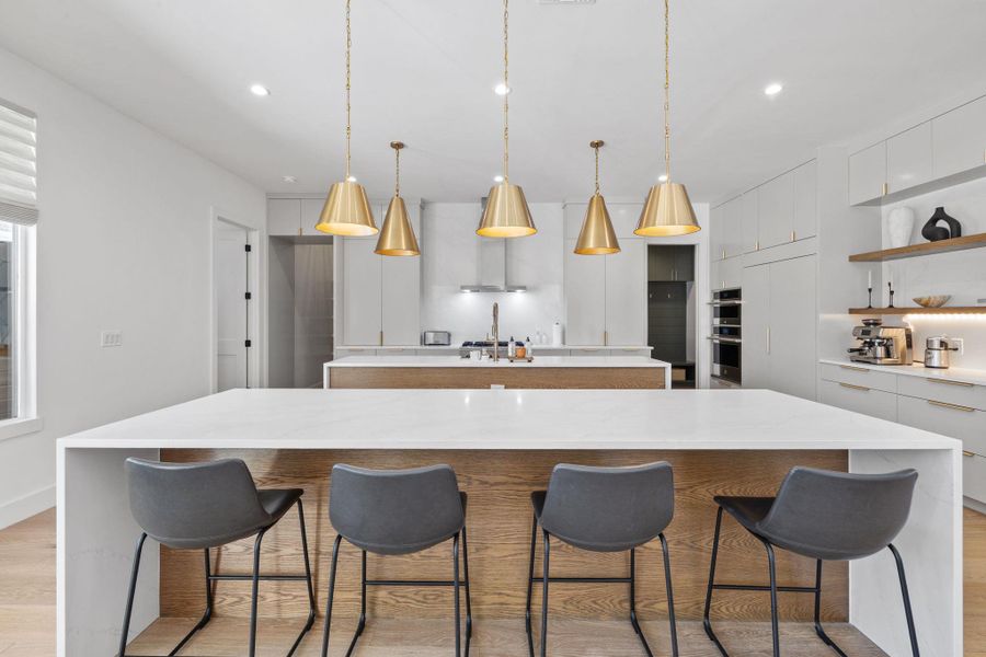 Kitchen with light wood-style flooring, modern cabinets, a breakfast bar, light stone counters, and open shelves