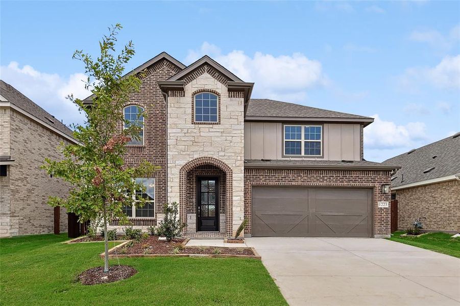 View of front of home with a garage and a front lawn