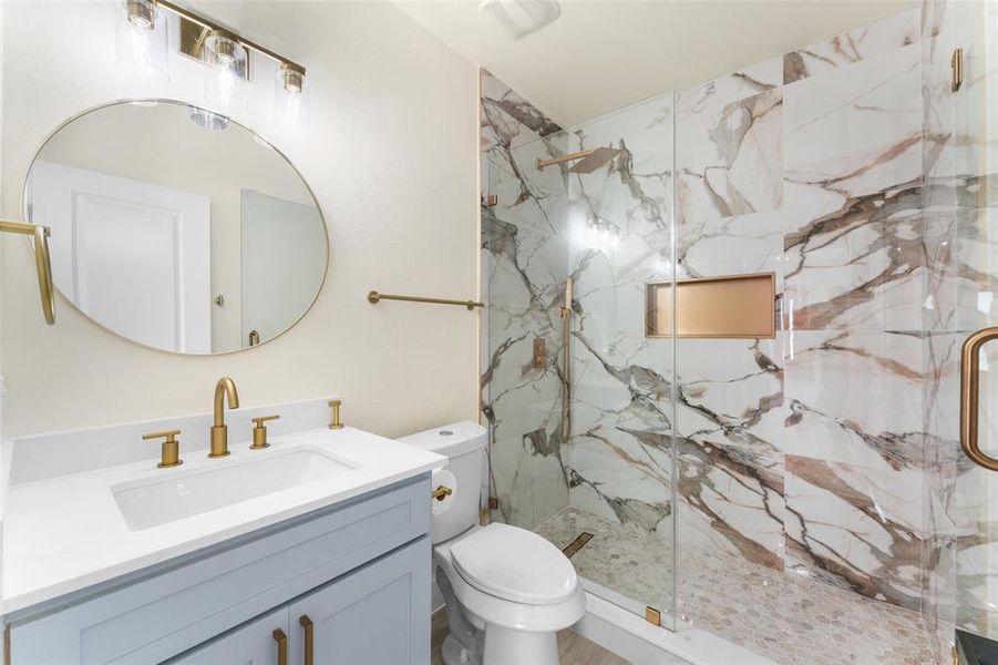 Bathroom featuring a marble finish shower and vanity