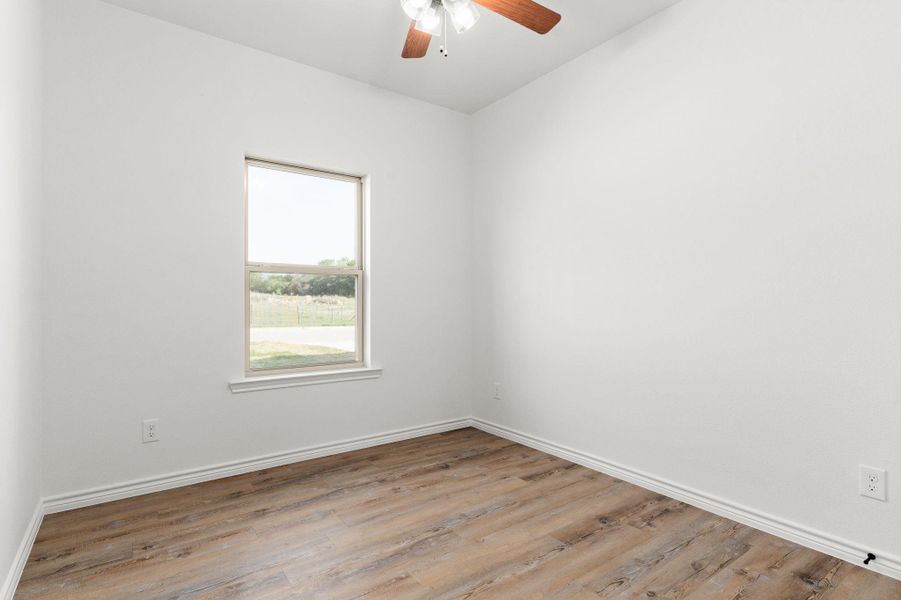 Unfurnished room with baseboards, a ceiling fan, and wood finished floors Unfurnished room with baseboards, a ceiling fan, and wood finished floors