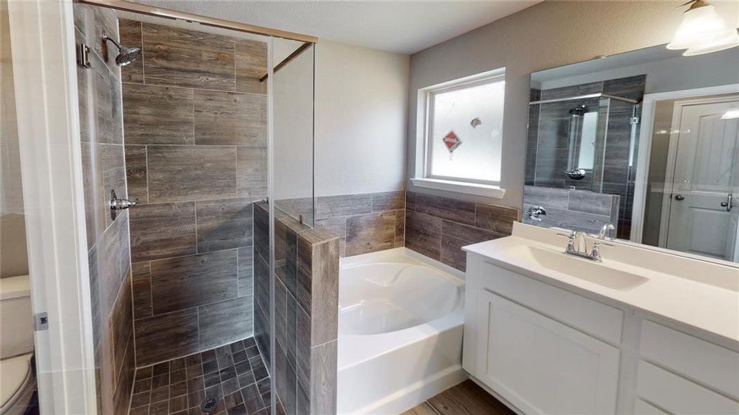 The luxurious primary bathroom features a walk-in shower with stylish tile work, a separate soaking tub, and a dual-sink vanity. The contemporary design and high-quality finishes create a spa-like atmosphere for daily relaxation. This is a picture of an Elise Floor Plan with another Saratoga Homes.