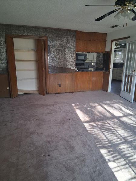 Kitchen with dark countertops, brown cabinetry, a ceiling fan, black appliances, and a textured ceiling Kitchen with dark countertops, brown cabinetry, a ceiling fan, black appliances, and a textured ceiling