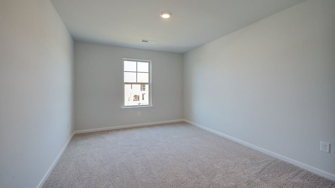 McKinley II spacious secondary bedroom with carpet flooring and natural light at Brighton in Locust Grove, GA.