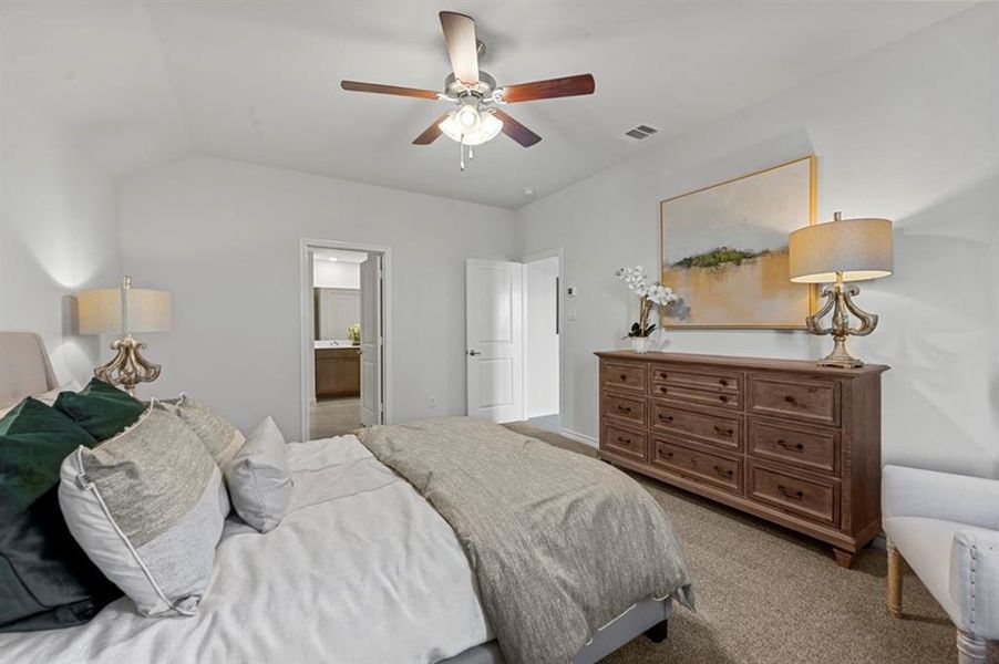Bedroom with light carpet, a ceiling fan, connected bathroom, and lofted ceiling