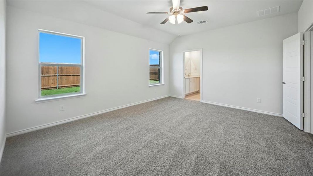 Spacious carpeted room featuring a vaulted ceiling and a ceiling fan Spacious carpeted room featuring a vaulted ceiling and a ceiling fan