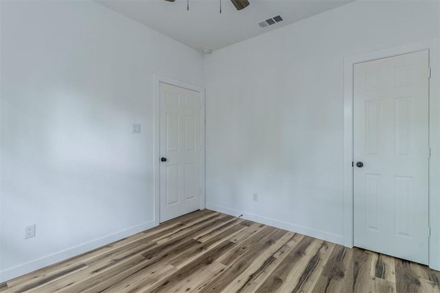 Empty room with wood finished floors, baseboards, and ceiling fan Empty room with wood finished floors, baseboards, and ceiling fan