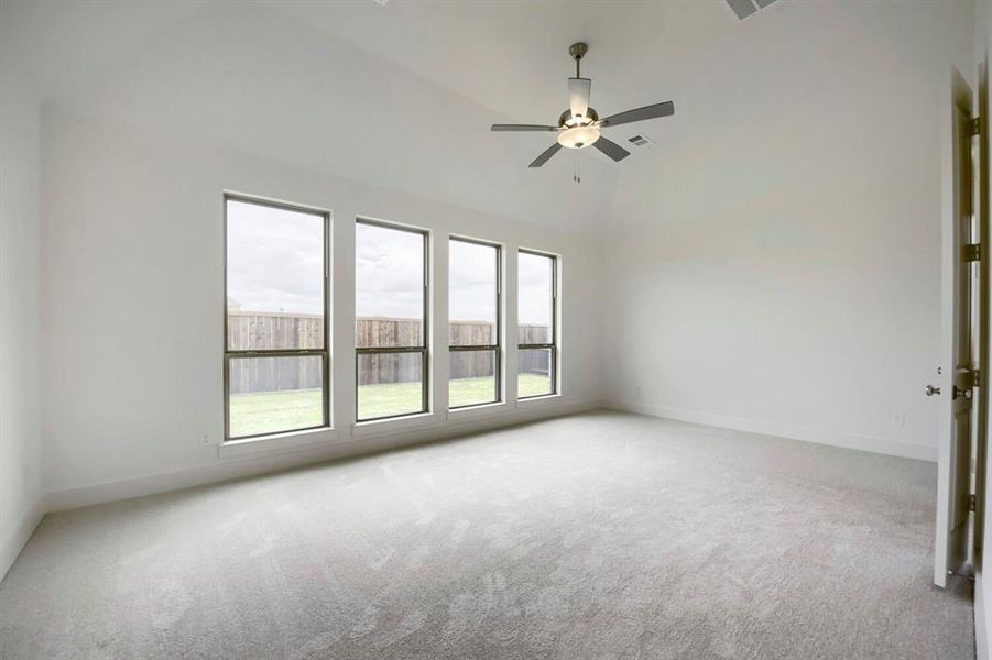 Spacious room featuring vaulted ceilings, a contemporary ceiling fan with integrated lighting, and plush grey carpeting Spacious room featuring vaulted ceilings, a contemporary ceiling fan with integrated lighting, and plush grey carpeting