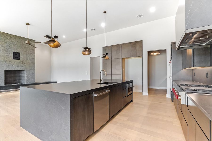 Kitchen featuring a sink, wall chimney range hood, modern cabinets, stainless steel appliances, and dark countertops Kitchen featuring a sink, wall chimney range hood, modern cabinets, stainless steel appliances, and dark countertops