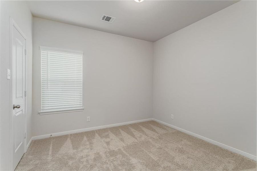 This bright and airy secondary bedroom is perfect for guests or family members. It features cozy carpeting, a ceiling fan, and large windows for natural light. Photos are from another Rylan floor plan.