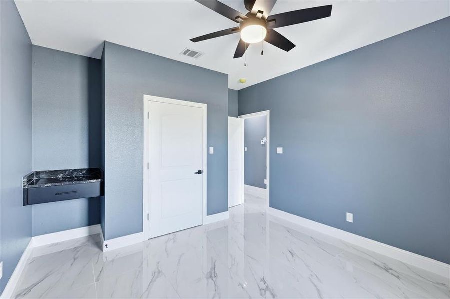Unfurnished bedroom with light marble finish flooring and a ceiling fan