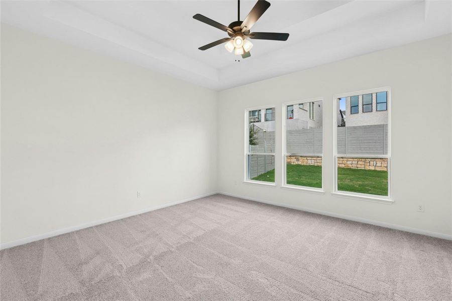 Unfurnished room with a raised ceiling, carpet flooring, and ceiling fan Unfurnished room with a raised ceiling, carpet flooring, and ceiling fan