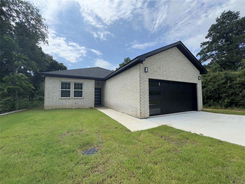 Ranch-style house featuring brick siding, an attached garage, a front yard, and concrete driveway