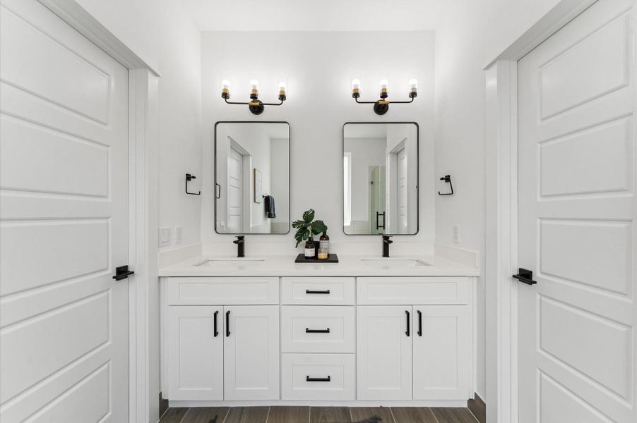 Indulge in everyday luxury in this elegant primary bathroom, where a freestanding soaking tub and a spacious walk-in shower offer the best of both worlds. The frameless glass shower enclosure showcases elegant tilework and dual showerheads, while the tub invites relaxation beneath a statement light fixture. A double vanity with quartz countertops and individual mirrors adds modern sophistication, and soft neutral tones create a serene, spa-like ambiance that elevates your daily routine.
