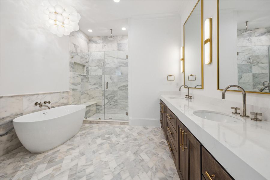 Primary bathroom features a Sterling Unwind freestanding oval soaking tub with Kallista One wall-mounted faucet, framed glass shower with Laticrete shower system, and tastefully crafted English-inspired stacked crown moldings. Primary bathroom features a Sterling Unwind freestanding oval soaking tub with Kallista One wall-mounted faucet, framed glass shower with Laticrete shower system, and tastefully crafted English-inspired stacked crown moldings.