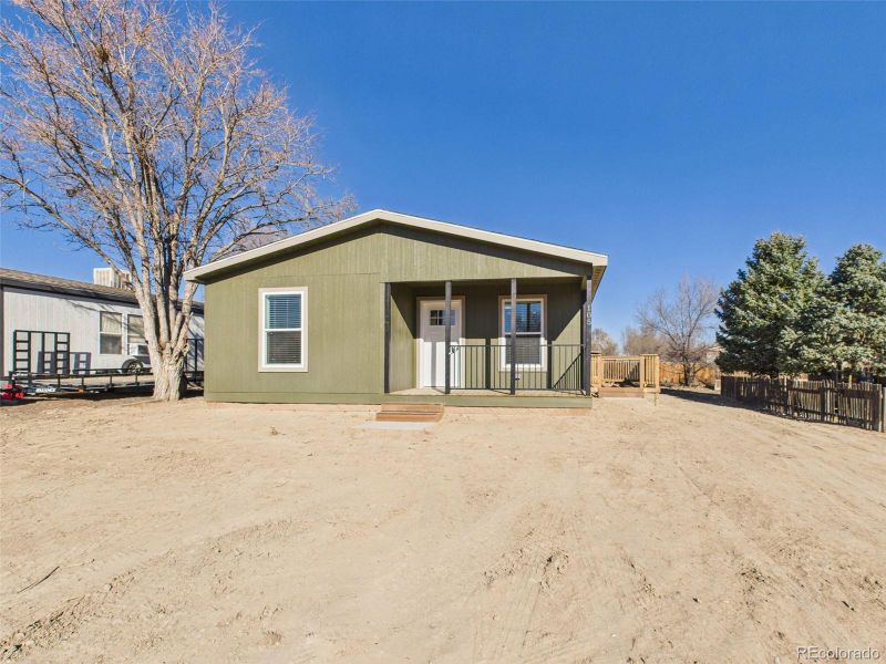 Front Exterior – Crisp curb appeal with a contemporary green facade, covered entry porch, and wood deck, all set on a generous lot with room to personalize the landscaping.