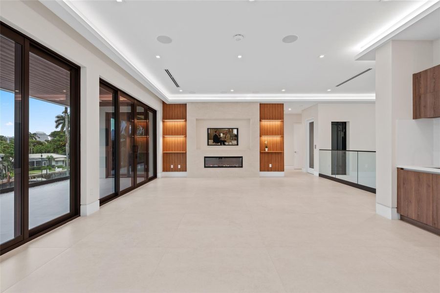 Spacious upstairs living area with sleek built-in wet bar, modern fireplace, and custom wood accents creating the perfect entertainment retreat. Spacious upstairs living area with sleek built-in wet bar, modern fireplace, and custom wood accents creating the perfect entertainment retreat.