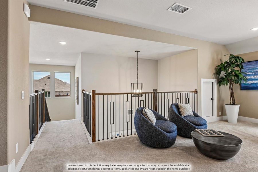 Upstairs loft with iron and wood stair railing, two blue accent chairs, and a pendant light fixture over carpet flooring Upstairs loft with iron and wood stair railing, two blue accent chairs, and a pendant light fixture over carpet flooring