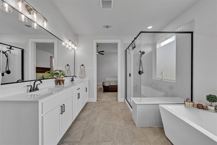 Spacious bathroom featuring a double vanity with stone countertops, a large framed mirror, and matte black fixtures