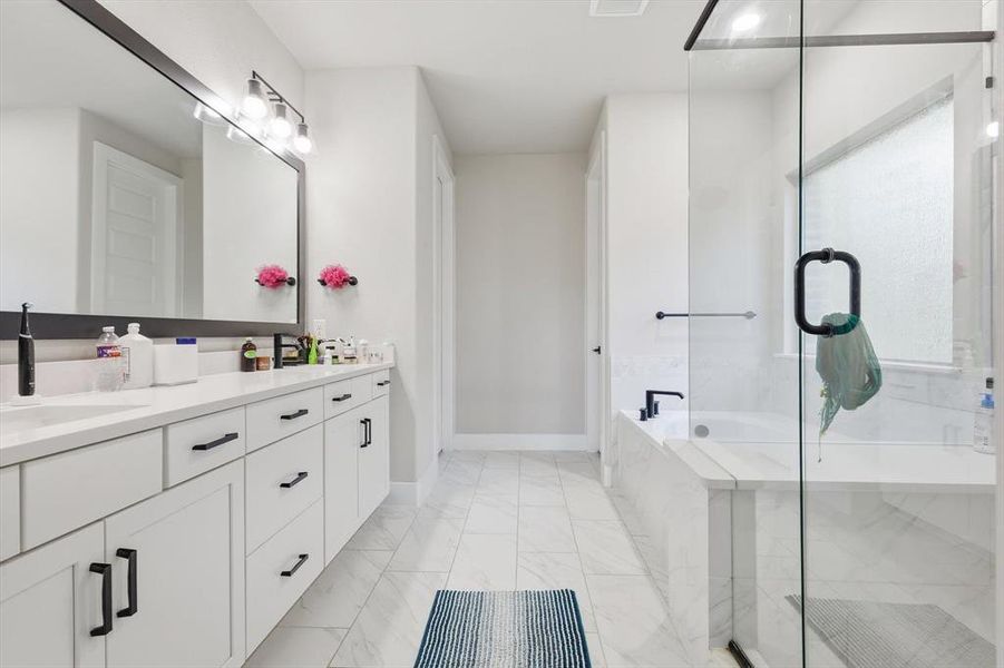 Full bathroom featuring a garden tub, vanity, a shower stall, and light marble finish flooring