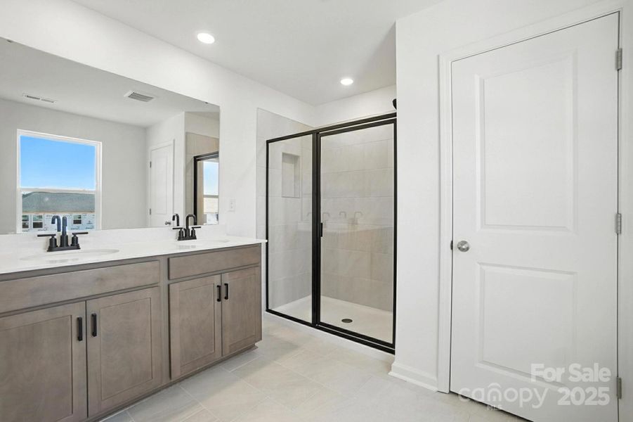 Primary bathroom with private water closet, linen closet, tile shower and dual vanity