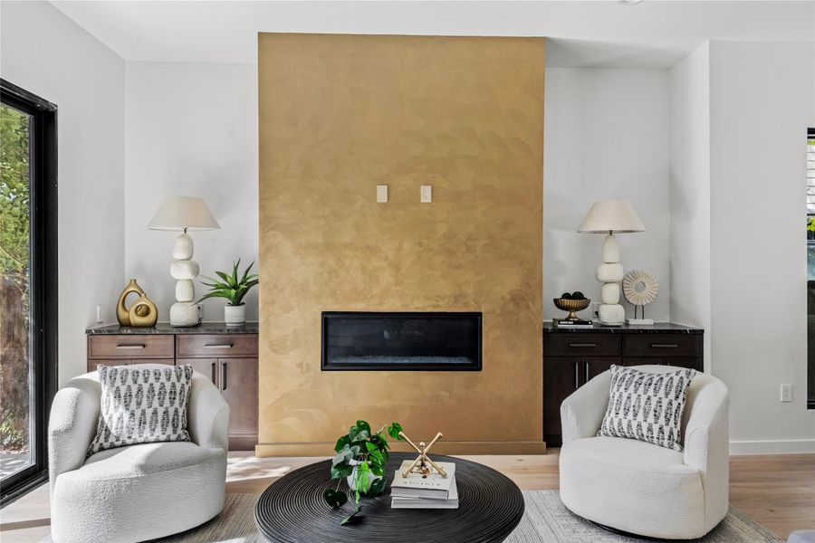 Sitting room featuring a glass covered fireplace and wood finished floors