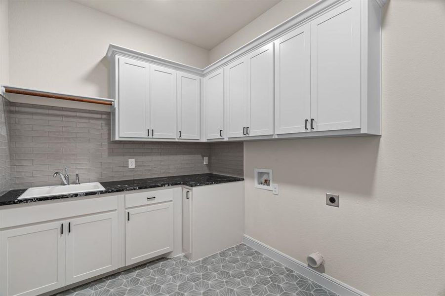 Laundry Room is Complete with Concrete Tile Floors, Abundant Cabinetry, Sink & Extra Fridge or Freezer Space