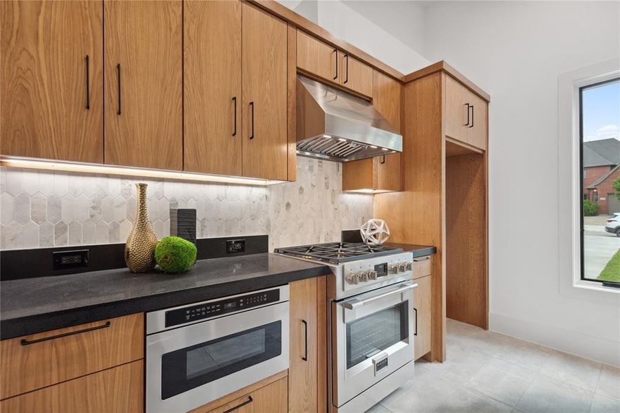 Kitchen with appliances with stainless steel finishes, backsplash, and light tile flooring