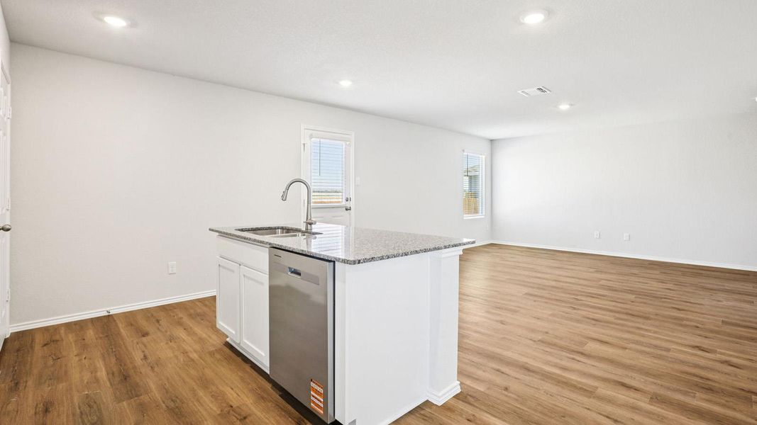 Kitchen island featuring a stainless steel sink with a high-arc faucet, integrated dishwasher, and granite countertop