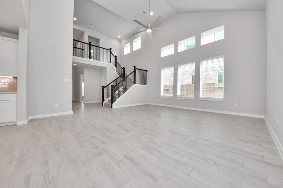 Family room flooded with natural light through the expansive windows.  The premium tile flooring adds a touch of luxury to the space, creating the perfect setting for relaxing moments and cherished gatherings with loved ones. Sample photo of completed home with similar floor plan. Actual colors and selections may vary.