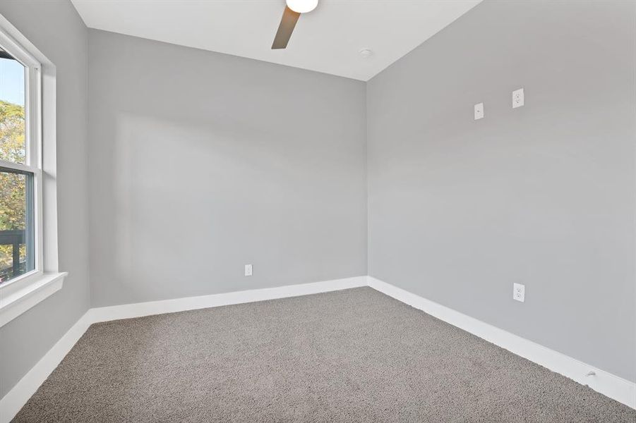 Carpeted empty room with ceiling fan and a wealth of natural light