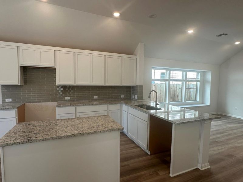 Kitchen featuring tasteful backsplash, white cabinets, light stone counters, recessed lighting, and dark wood-style floors Kitchen featuring tasteful backsplash, white cabinets, light stone counters, recessed lighting, and dark wood-style floors