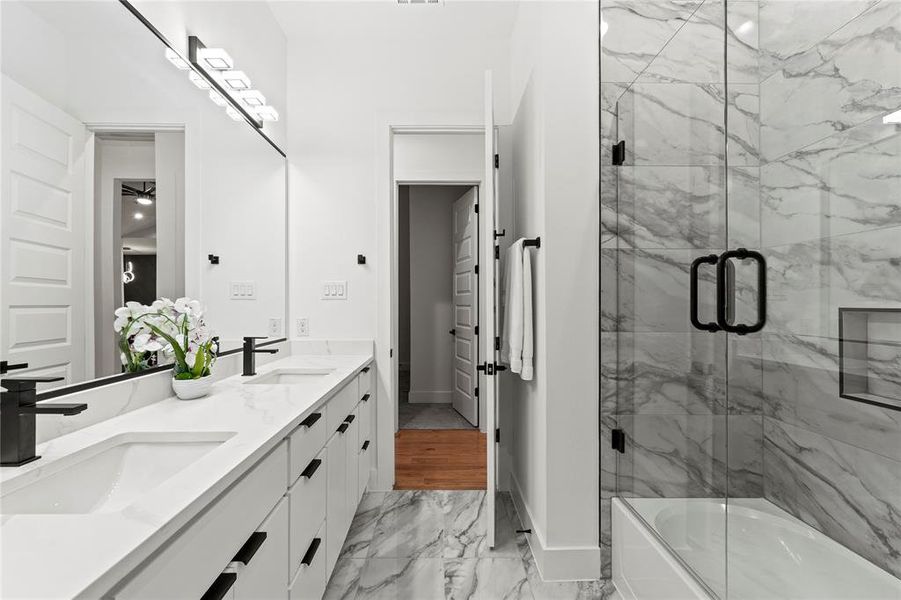 Bathroom featuring marble finish floor, double vanity, a sink, and baseboards