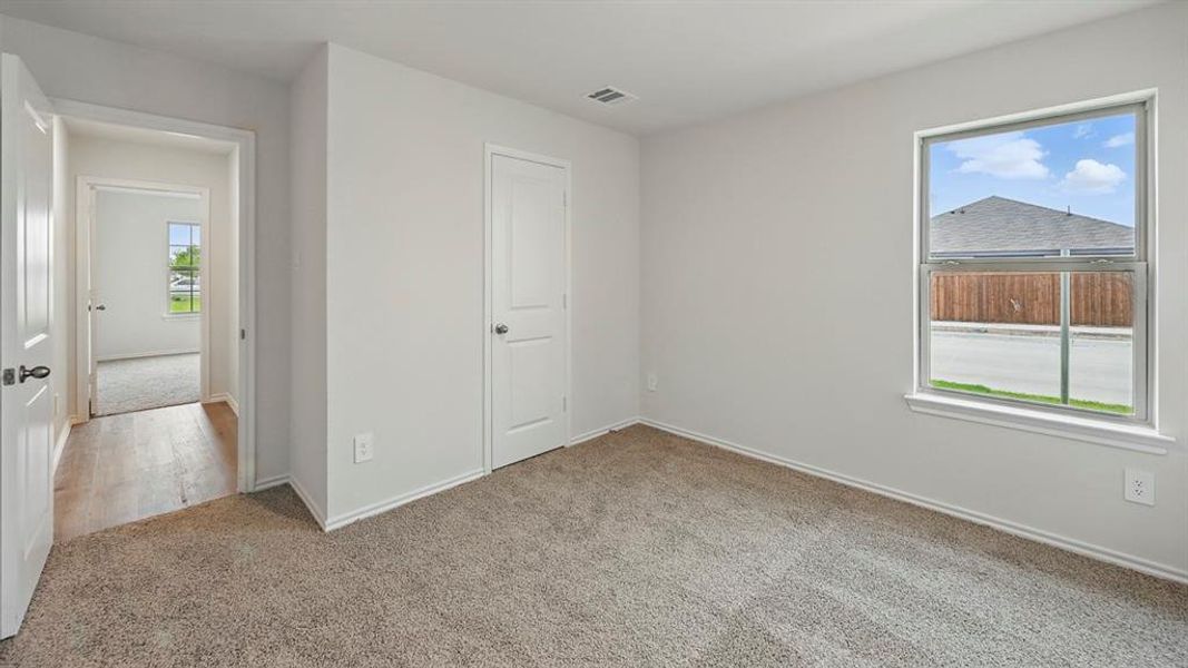 Unfurnished bedroom featuring light carpet and baseboards