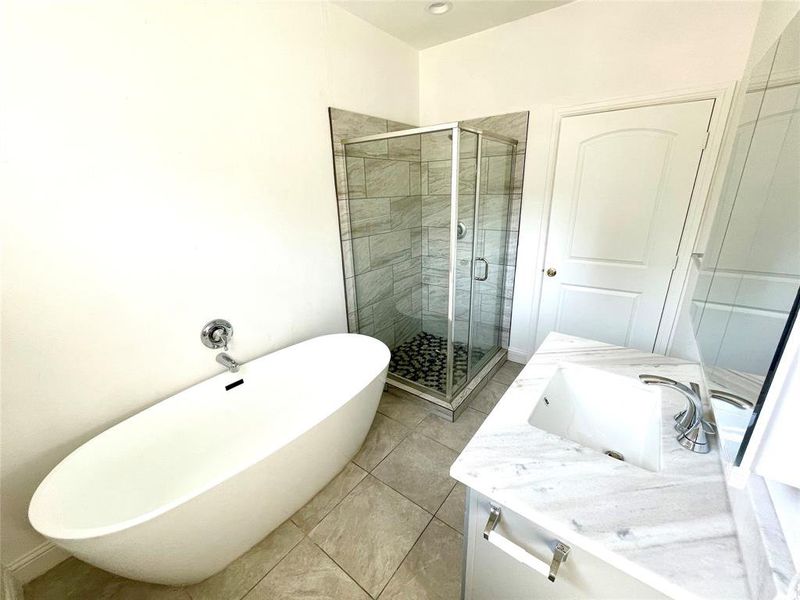 Bathroom featuring plus walk in shower, tile patterned flooring, and vanity