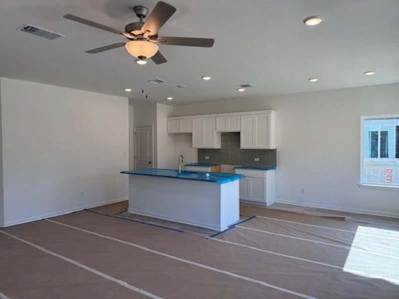 Kitchen with white cabinetry, an island with sink, dark countertops, and decorative backsplash Kitchen with white cabinetry, an island with sink, dark countertops, and decorative backsplash