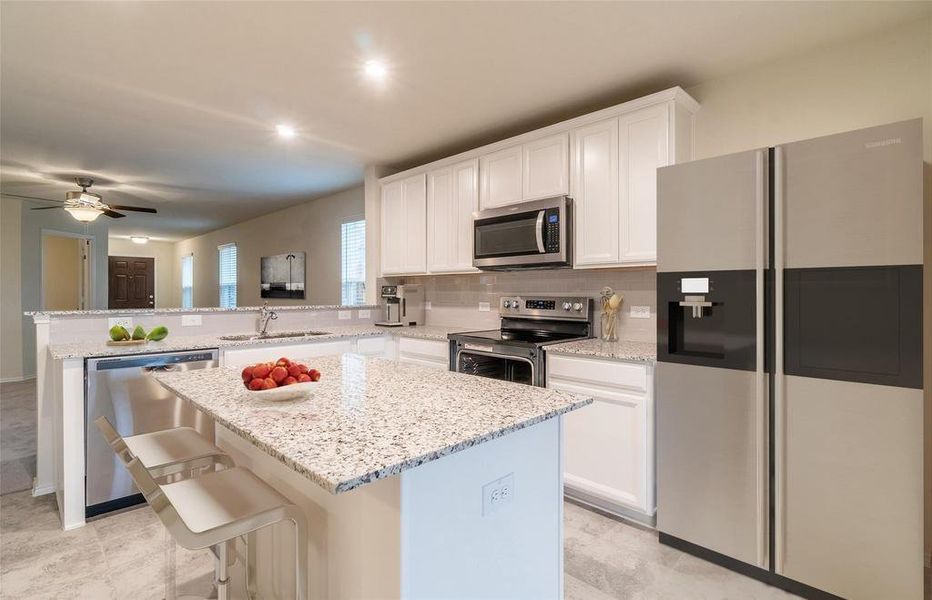 Kitchen featuring appliances with stainless steel finishes, decorative backsplash, white cabinetry, a center island, and a breakfast bar Kitchen featuring appliances with stainless steel finishes, decorative backsplash, white cabinetry, a center island, and a breakfast bar