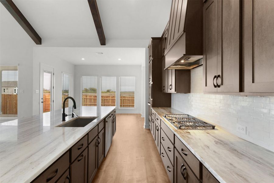Kitchen featuring dark brown cabinets, recessed lighting, light stone counters, light wood-style floors, and appliances with stainless steel finishes