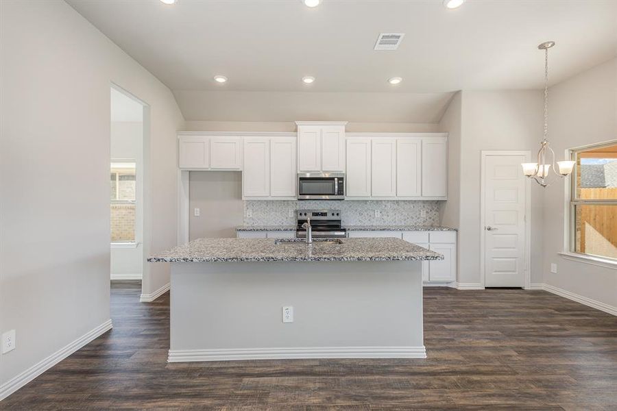 Kitchen with white cabinets, appliances with stainless steel finishes, dark hardwood / wood-style floors, and an island with sink