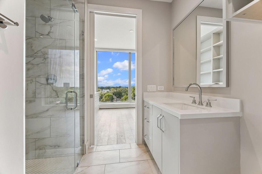A second en-suite guest bathroom with custom built-ins and glass-enclosed walk-in shower.