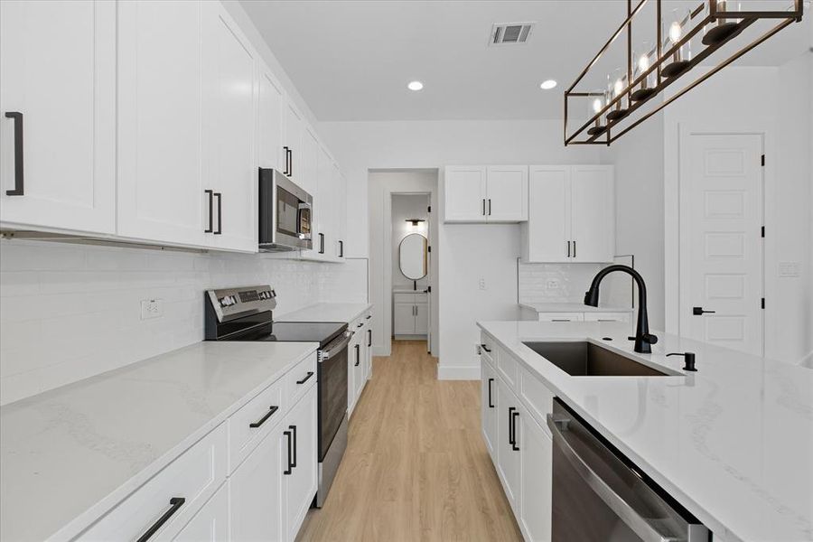 Kitchen featuring stainless steel appliances, light stone counters, tasteful backsplash, white cabinetry, and recessed lighting